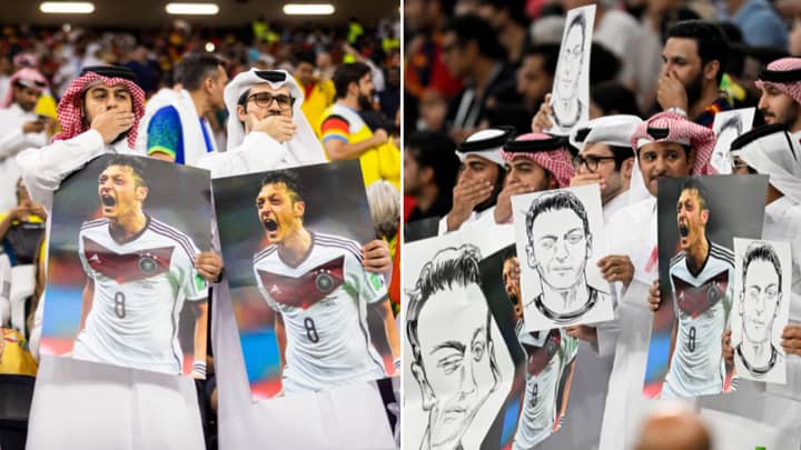 Des fans tiennent des photos de Mesut Ozil en se couvrant la bouche pendant le match Allemagne-Espagne.